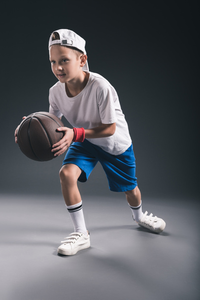 stylish boy playing basketball on grey background - Фото, изображение