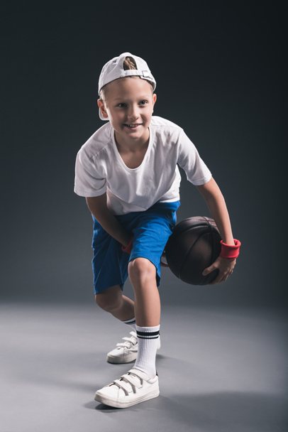 κομψό αγόρι παίζει μπάσκετ σε γκρίζο φόντο - Φωτογραφία, εικόνα