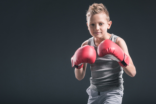 portrait of boy with red boxing gloves on black backdrop - Foto, Imagen