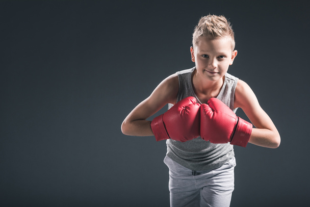 portrait of boy with red boxing gloves on black backdrop - Photo, Image