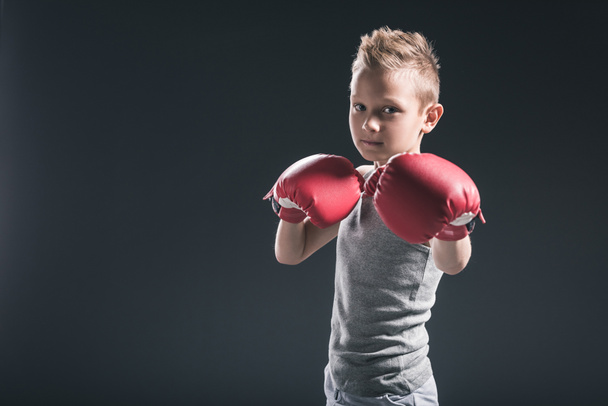 Portret van jongen met rode bokshandschoenen op zwarte achtergrond - Foto, afbeelding