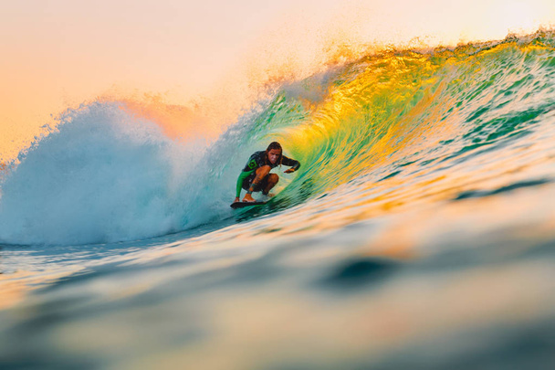 8 września 2018 r. Bali, Indonezja. Surfer jazdy na fali lufy o zachodzie słońca ciepły. Professional surfing w ocean, plaża Bingin - Zdjęcie, obraz