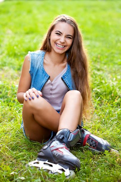 Girl wearing roller skates sitting on grass - Foto, afbeelding