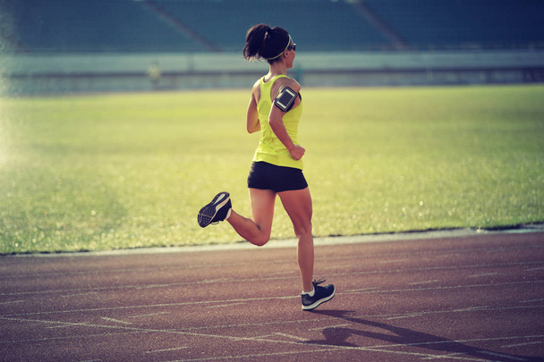 Young sportswoman running on stadium tracks - Фото, зображення