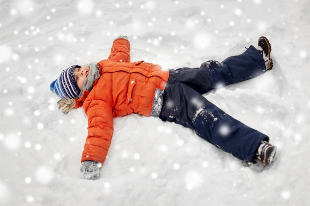 happy little boy making snow angels in winter - Foto, immagini