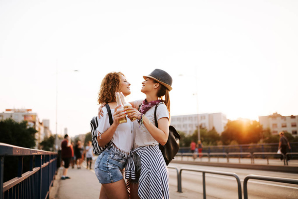 Girlfriends hugging and drinking in the summer in the city. - Foto, Bild