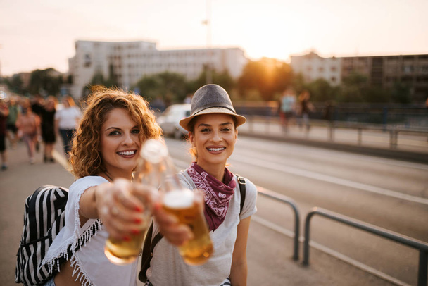 Cheers! Close-up of two festival party girls toasting in the summer in the city. - Foto, imagen