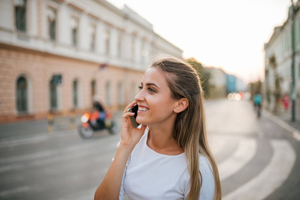 Close-up of a beautiful girl talking on the phone in the city. - 写真・画像