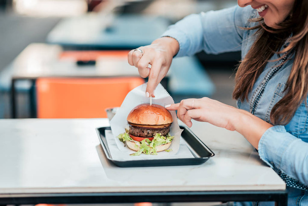 Close-up image of young woman eating hamburger. - Zdjęcie, obraz