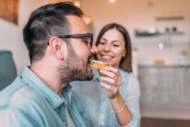 Close-up image of husband eating sandwich from his wife's hand. - Foto, Imagem