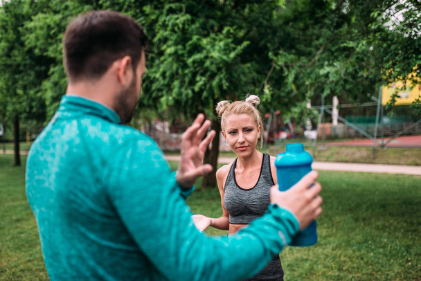 Personal trainer and young woman discussing fitness plan outdoors. - 写真・画像
