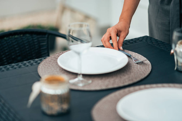 Female person setting up table for dinner at home. - Photo, image