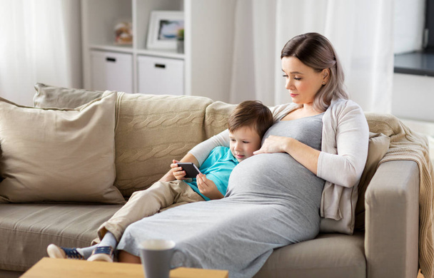 pregnant mother and son with smartphone at home - Foto, imagen