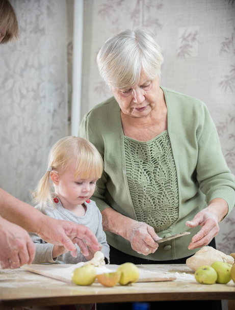Uma velhota a fazer tartes com uma menina
 - Foto, Imagem