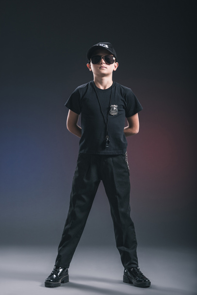 boy in policeman uniform and sunglasses with whistle on dark background - Fotografie, Obrázek