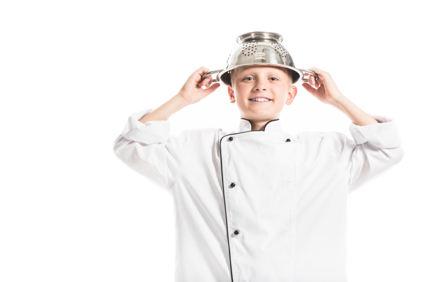 portrait of preteen boy in white chef uniform with colander on head isolated on white - Fotó, kép