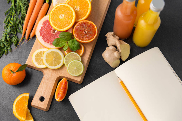 close up of fruits, juices and notebook on table - Фото, зображення