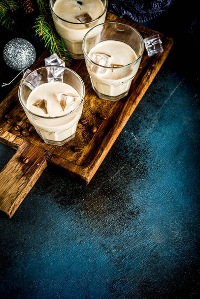 Ирландский сливочный коктейль или ликер, традиционный зимний рождественский напиток, темный ржавый фон с ветвями елки, кофейные зёрна и рождественские украшения, копировальное пространство
 - Фото, изображение