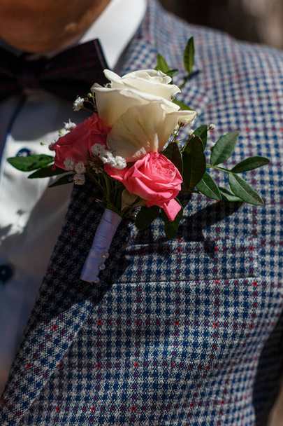 Elementos de la ropa del novio el día de la boda. Mariposa azul, esmoquin y boutonniere con rosas blancas
. - Foto, Imagen