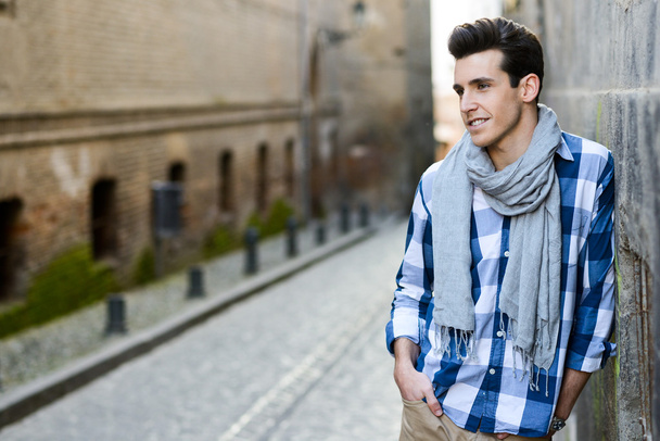 Handsome man with modern hairstyle smiling in urban background - Photo, Image