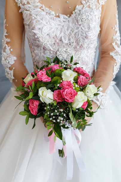 Наречена в мереживному сукні, що тримає весільний букет з білих і рожевих троянд
. - Фото, зображення