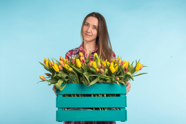 Gyönyörű női Kertész gazdaság doboz tulipán a kék háttér - Fotó, kép
