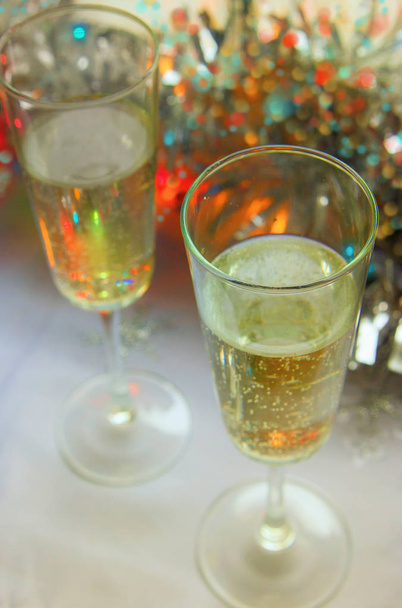 Photo of two champagner glasses on festive table with christmas ornaments and bokeh background. - Photo, image