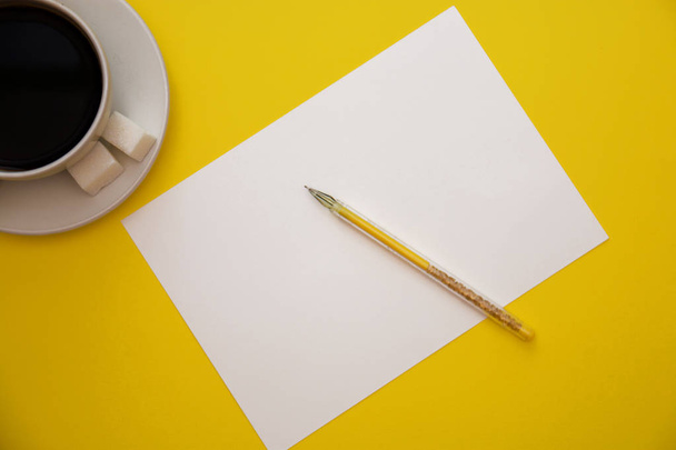 pen white paper and coffee Cup on yellow background with copy space top view. - Fotografie, Obrázek