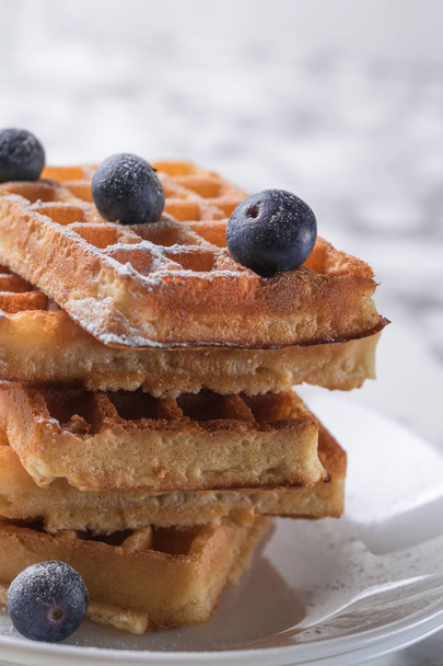 Rectangular waffles on a white plate decorated with blueberries with marbled background. copy space - Foto, afbeelding