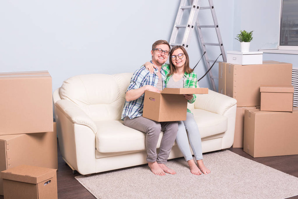 New apartment, relocation and moving concept - Happy couple sitting on sofa in their new flat - Photo, Image