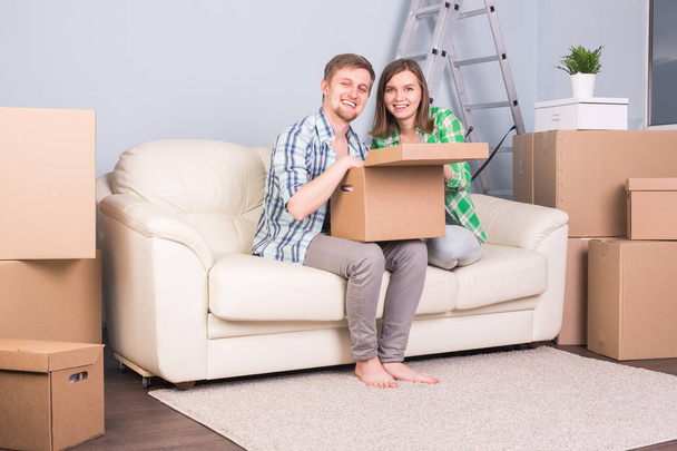 Mudanza, nuevo concepto de apartamento y reubicación - pareja feliz abriendo su caja juntos debido a mudarse a un nuevo apartamento
 - Foto, Imagen