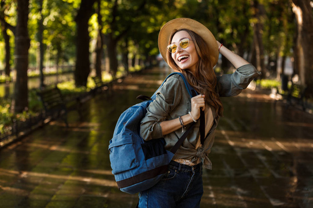 Image of excited beautiful young happy woman walking outdoors with backpack. - Фото, зображення