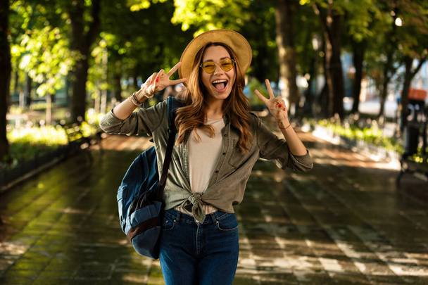 Image of excited beautiful young happy woman walking outdoors with backpack. - Foto, immagini