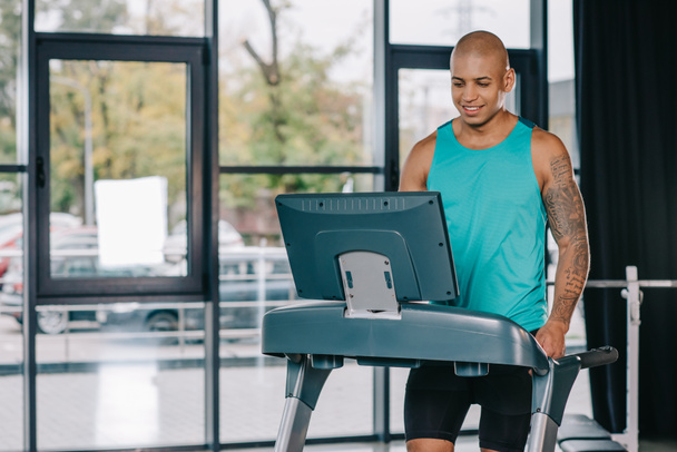 smiling african american male athlete on treadmill at gym - Foto, afbeelding