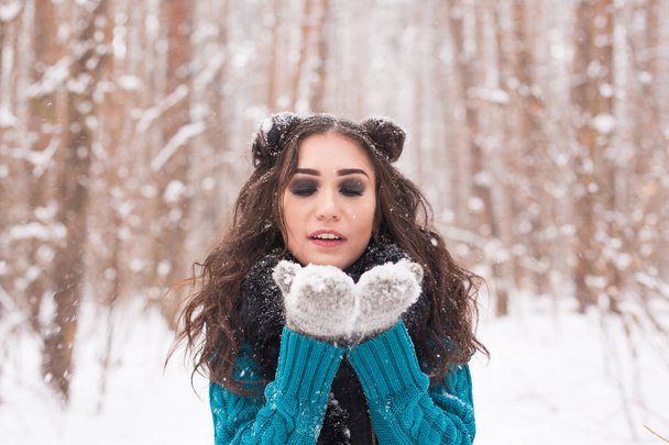 Noël, vacances et concept de saison - Jeune femme brune heureuse soufflant de la neige en hiver nature
 - Photo, image