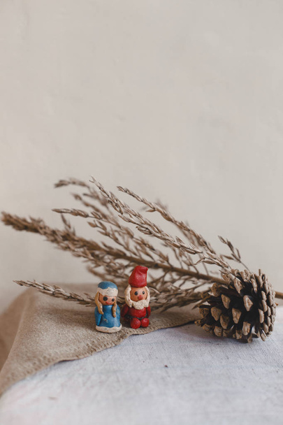新しい年、サンタ クロース (父フロスト) と雪の乙女、クリスマス カード。織物リネン表面に粘土の置物。コーンと装飾のような乾いた花. - 写真・画像