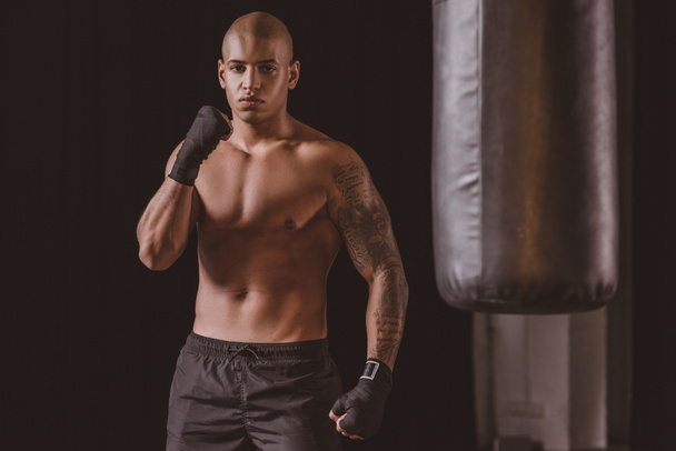 confident african american boxer posing near punching bag at gym - Photo, Image