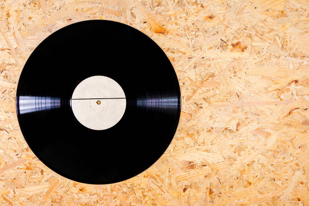 Black color vinyl record with white label on plywood background - Photo, Image