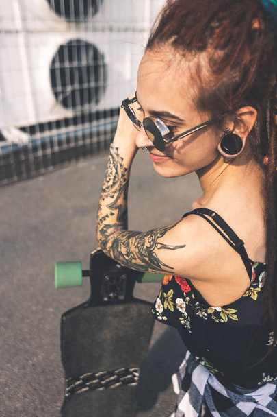 young girl with tattoo and dreadlocks on urban industrial background - Foto, afbeelding