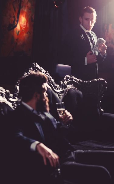 Boss gives orders. Mature man with long beard talks to his assistant. Bearded man with serious face and champagne glass. Success, order, authority, wealthy lifestyle, business, money concept - Photo, image