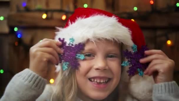 Cute little Santa girl playing with snowflakes over christmas lights background. - Footage, Video