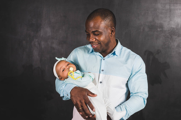African American man holding a child against a black wall - Photo, image