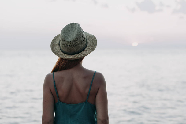 Женщина смотрит на закат на морском горизонте
 - Фото, изображение