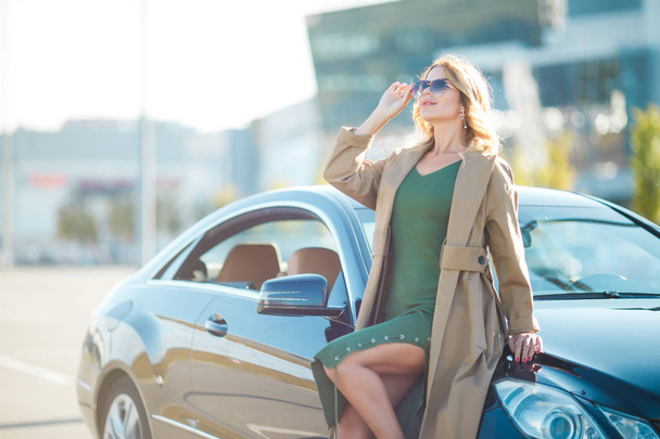 Photo of woman in sunglasses standing by black car - Foto, afbeelding