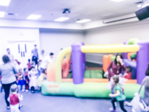 Motion brouillé divers enfants multiethniques apprécient le jeu gonflable de saut de maison de rebond. Parents et enfants déconcentrés à la fête d'Halloween de l'école intérieure au Texas, en Amérique
 - Photo, image