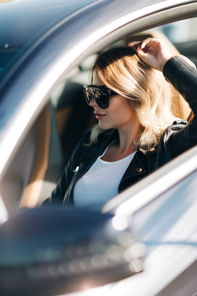 Picture of woman on sunglasses sitting in car. - Zdjęcie, obraz