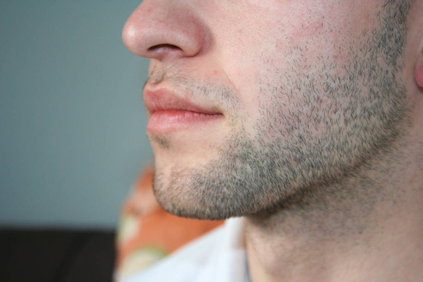 Un visage d'homme avec une barbe légère. Quelques jours barbe sur le menton du gars. Macro photo prise à partir du profil
. - Photo, image