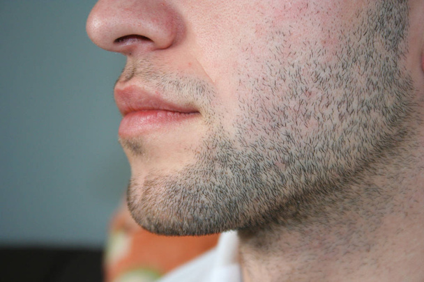 Mužská tvář s mírným vousy. Pár dní vousy na bradě toho chlapa. Makro snímek pořízený z profilu. - Fotografie, Obrázek