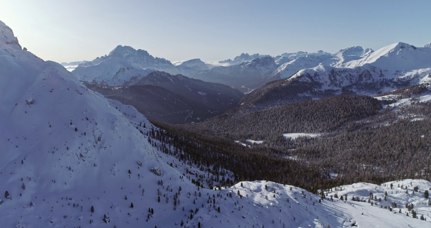 Backward aerial to snowy alpine valley with woods forest at Valparola pass.Sunny sunset or sunrise,clear sky.Winter Dolomites Italian Alps mountains outdoor nature establisher.4k drone flight - Footage, Video