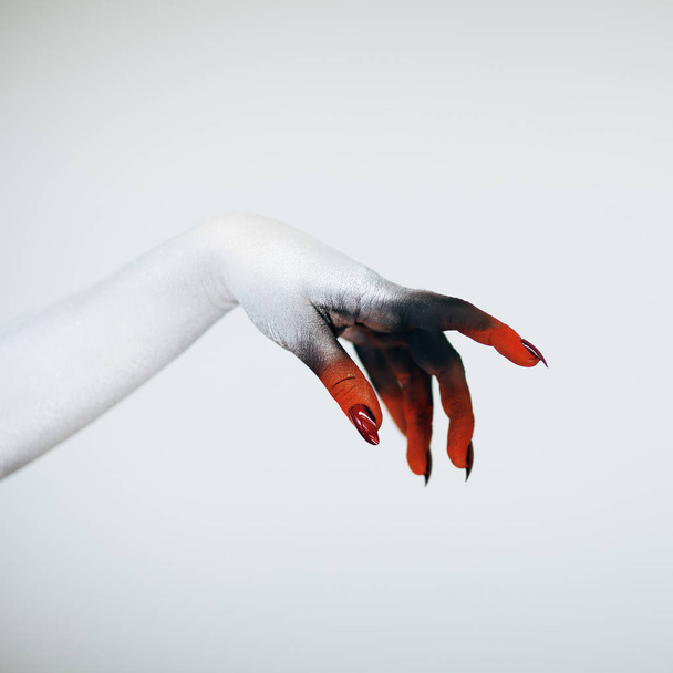 Creepy Halloween monster witch hand with white, red and black make up and long creepy fingernails in front of white background  - Foto, immagini